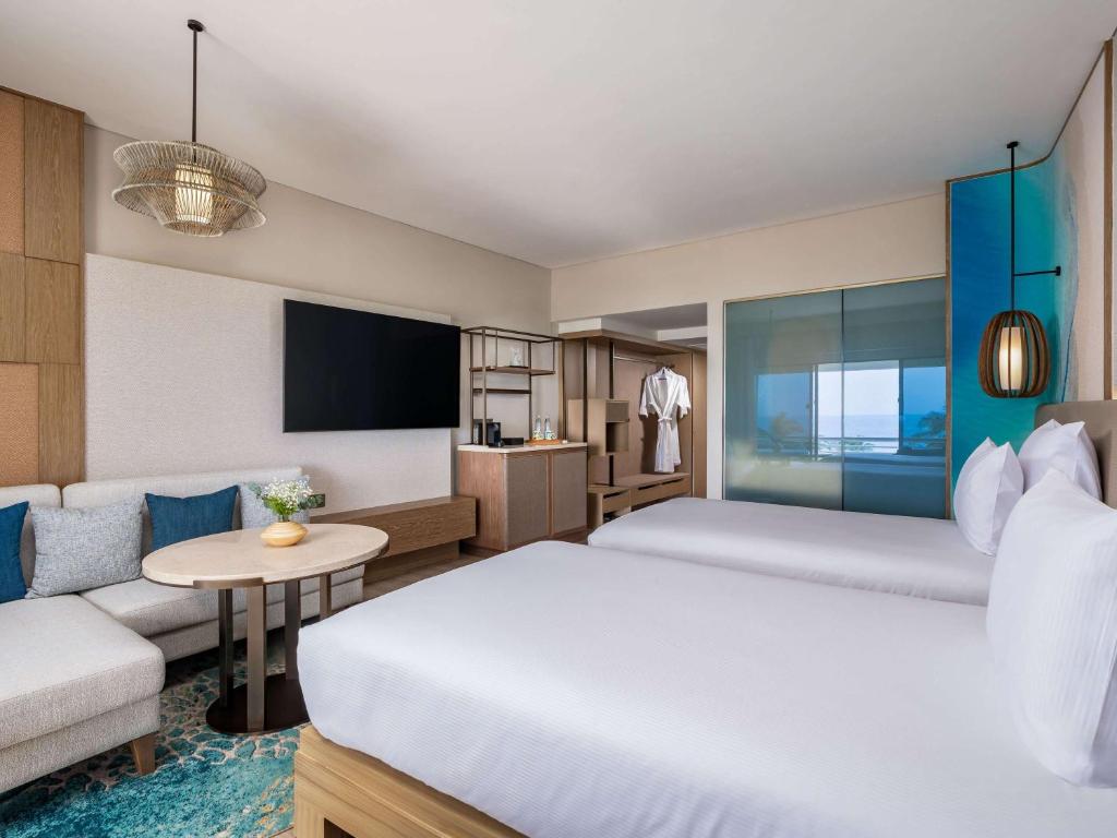 a hotel room with a bed and a couch at Pullman Phuket Karon Beach Resort in Karon Beach