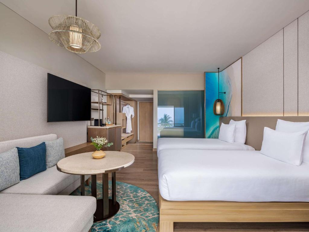 a hotel room with two beds and a couch at Pullman Phuket Karon Beach Resort in Karon Beach