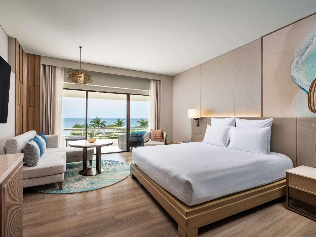 a bedroom with a bed and a living room at Pullman Phuket Karon Beach Resort in Karon Beach