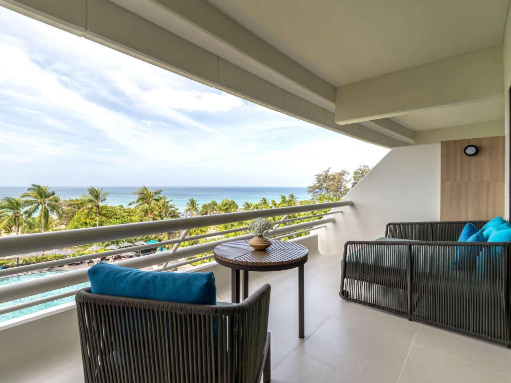 a balcony with chairs and a view of the ocean at Pullman Phuket Karon Beach Resort in Karon Beach