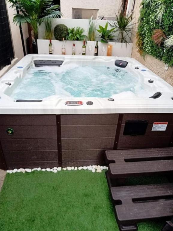 un bain à remous dans une arrière-cour avec de l'herbe verte dans l'établissement Maison 10 pièces Spa jacuzzi Paris Airport CDG jardin arboré clos, à Tremblay-en-France