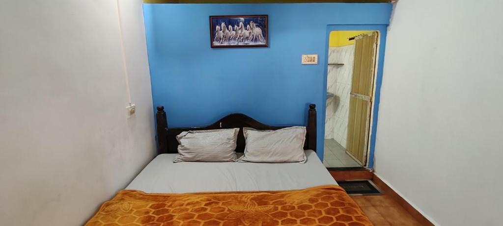 a room with a bed with a blue wall at Laxmi in Arambol
