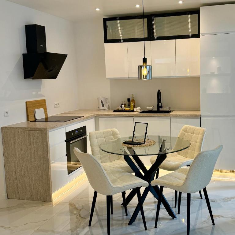 une cuisine avec une table et des chaises en verre dans l'établissement Le Soleil Tropezien, Somptueux 2 pièces rénové, Terrasse, Centre, Vue Mer, Menton, à Menton