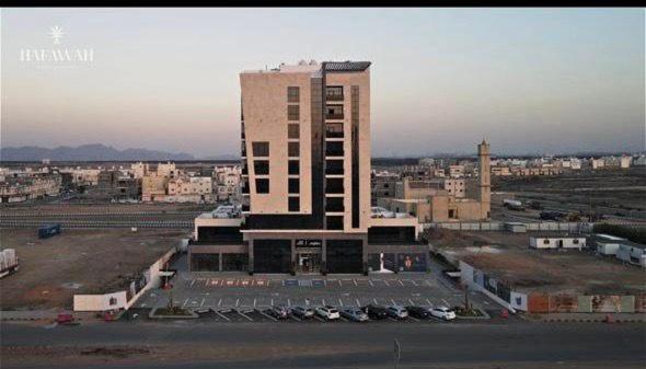un grand bâtiment avec des voitures garées dans un parking dans l'établissement Hafawah Resort, à Médine