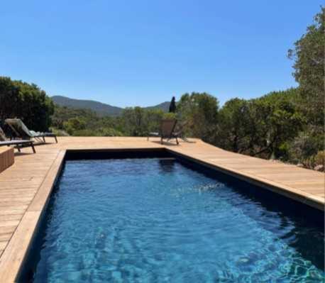 une piscine d'eau bleue et un banc dans l'établissement Maison de standing avec piscine vue mer Corse du sud de 6 à 14 personnes 7 chambres, à Coti-Chiavari