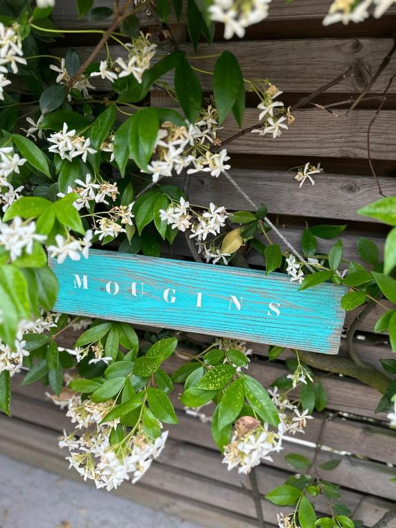 un panneau bleu qui dit motegina suspendu sur un mur avec des fleurs dans l'établissement Villa Felicita, à Mougins