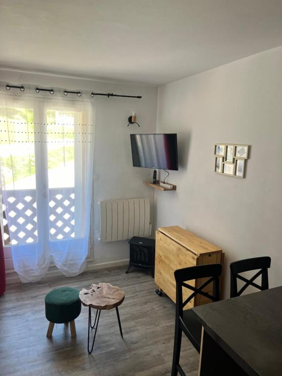 un salon avec une télévision, une table et des chaises dans l'établissement Studio à La Foux d 'Allos, à La Foux d'Allos