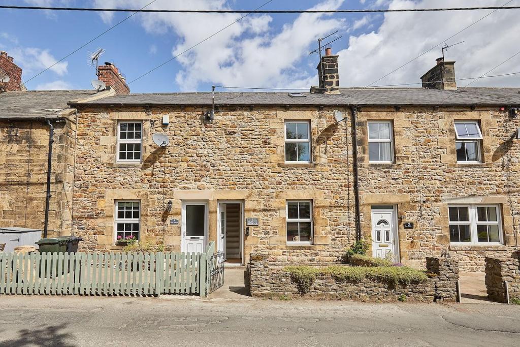 an old stone house with a white fence in front of it at Traditional cottage with brand new Woodburner in Wark