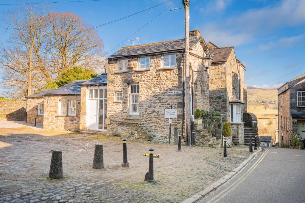 an old stone house with a sign in front of it at The Old Weigh House in Kirkby Lonsdale