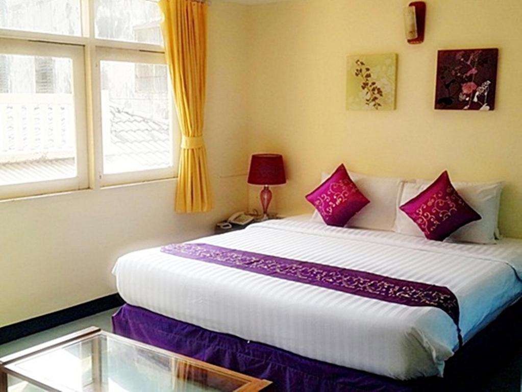 a bedroom with a large bed with pink pillows at Sawasdee Sukhumvit Inn in Bangkok