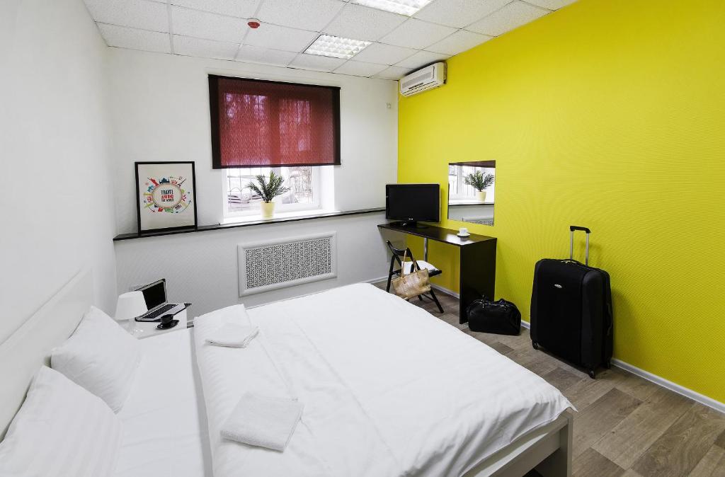 1 dormitorio con cama blanca y pared amarilla en Maxi House Hostel en Rostov-on-Don