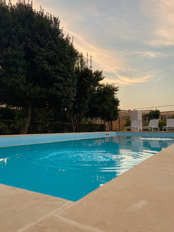 una piscina blu con alberi sullo sfondo di Villa De Pietro a Cursi