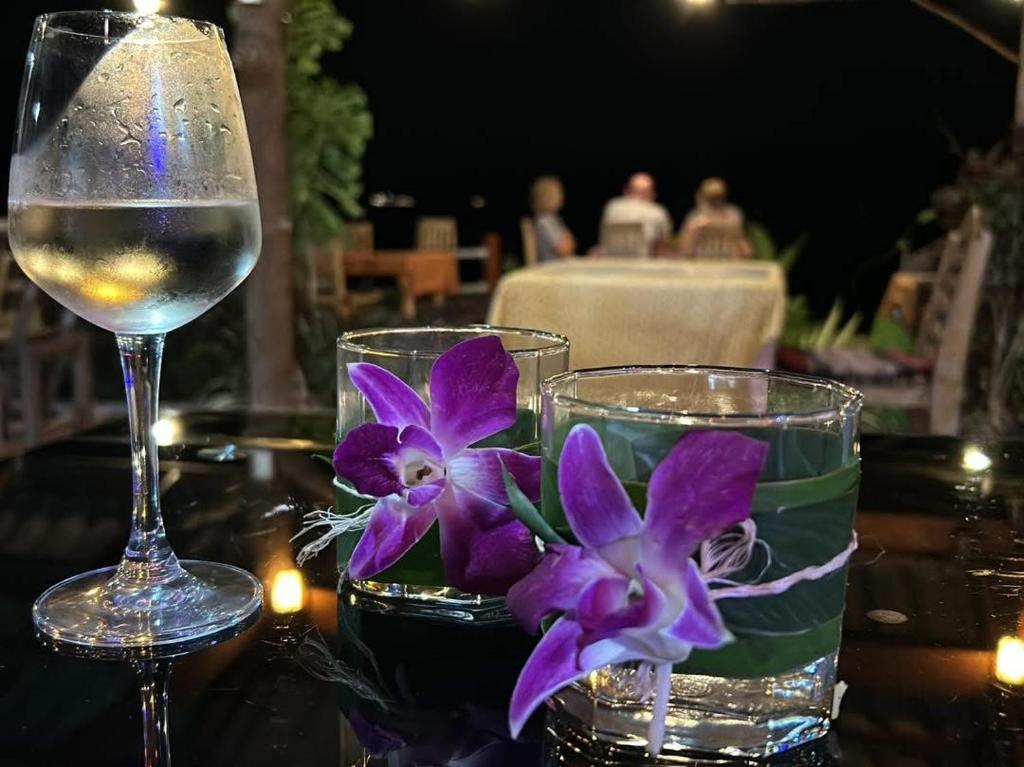un verre de vin et des fleurs violettes sur une table dans l'établissement Phukhao thong, à Ban Bang Chak