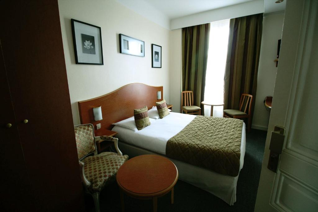 una camera d'albergo con letto e sedia di Hôtel Crystal Reims Centre a Reims