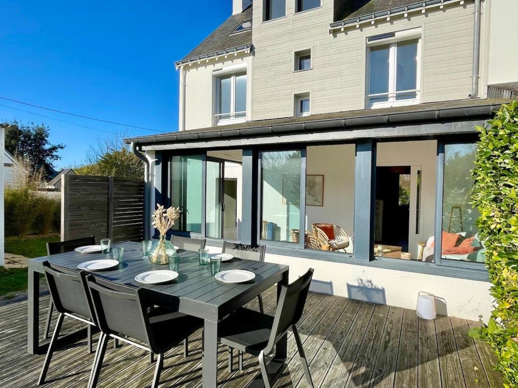 une table et des chaises noires sur une terrasse avec une maison dans l'établissement Kerlud, maison avec garden, à Locmariaquer