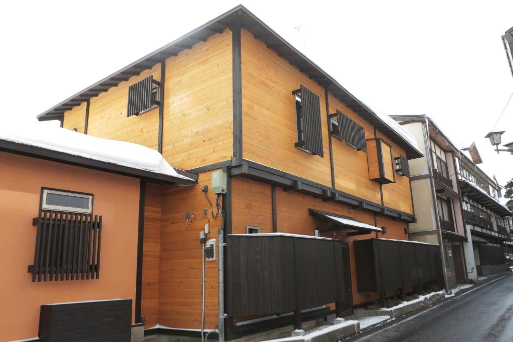 a wooden building with windows on a street at 貸切温泉旅館ー倉持ー湯畑まで徒歩1分 in Kusatsu