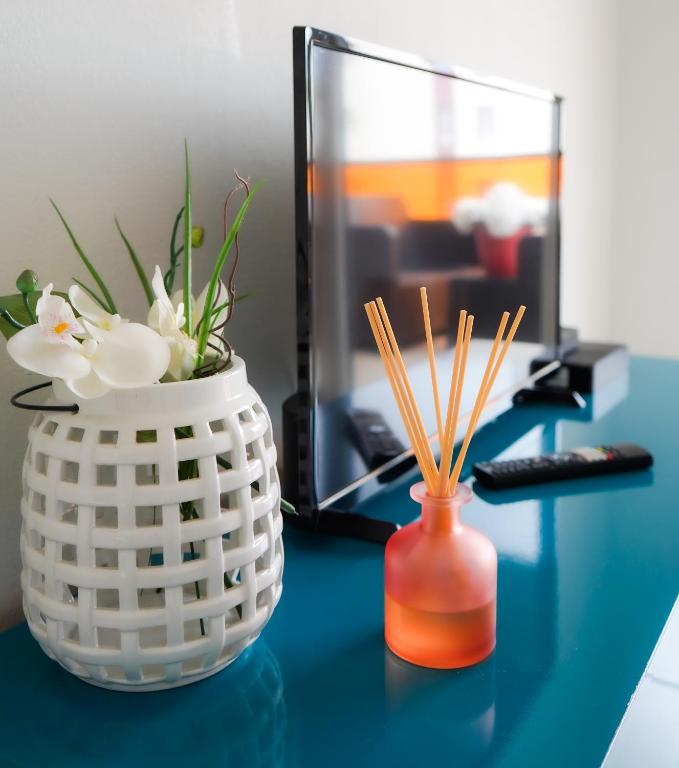a blue desk with a vase with flowers and a computer at Bel appartement climatisé avec parking in Perpignan