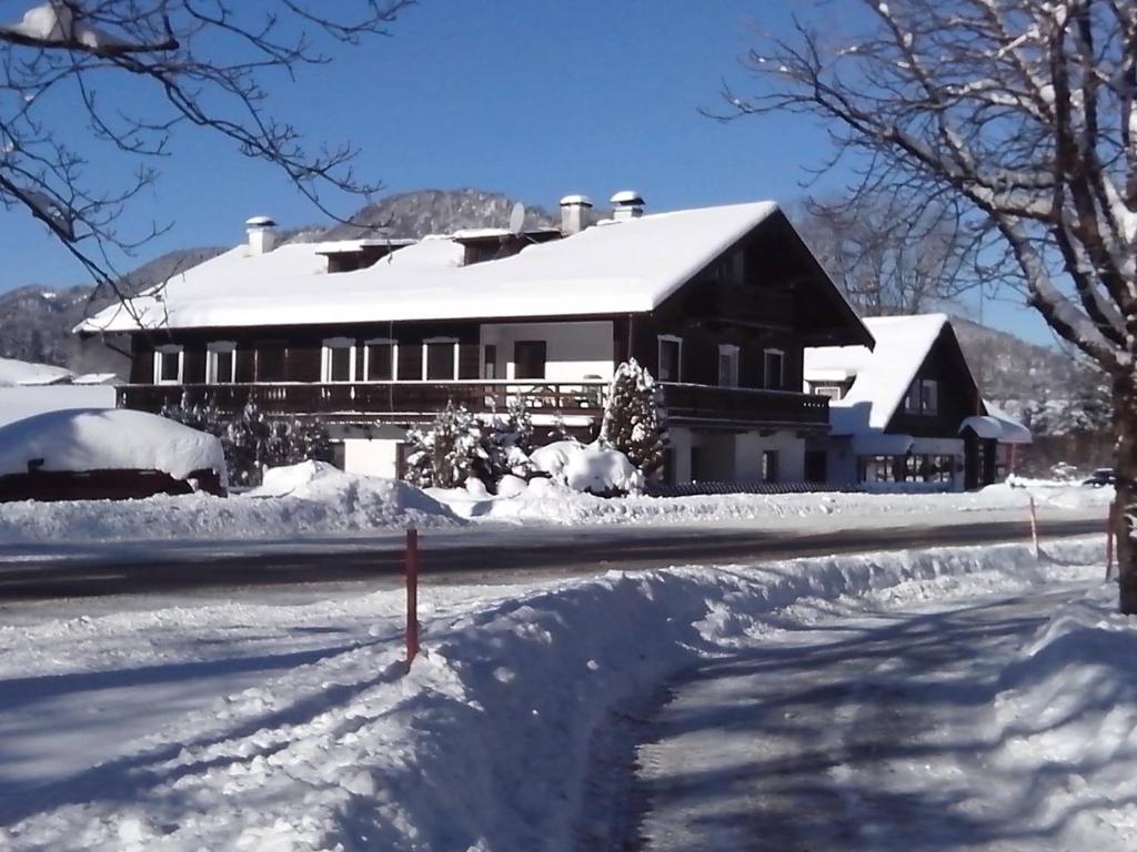 a house covered in snow in front of a road at Pension Rauschberghof in Ruhpolding