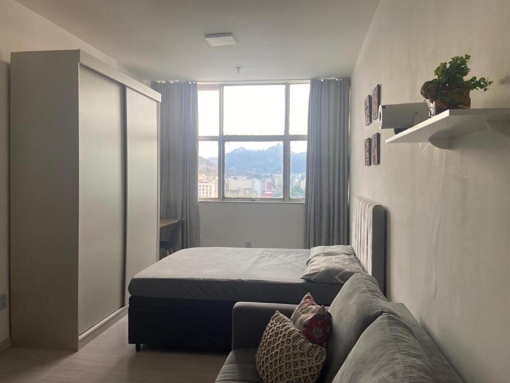 une chambre avec un lit, un canapé et une fenêtre dans l'établissement Apê da Praça, à Rio de Janeiro