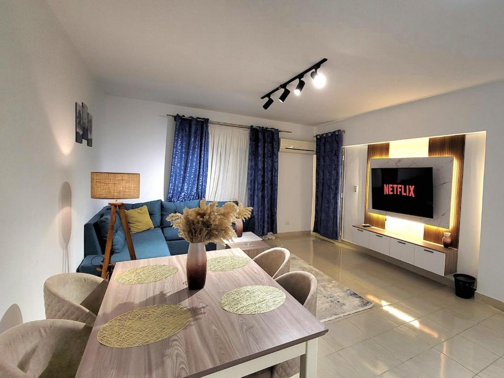 un salon avec une table et une télévision dans l'établissement Rehab Elegant Apartment - New Cairo, à Burg el-Ḥudûd