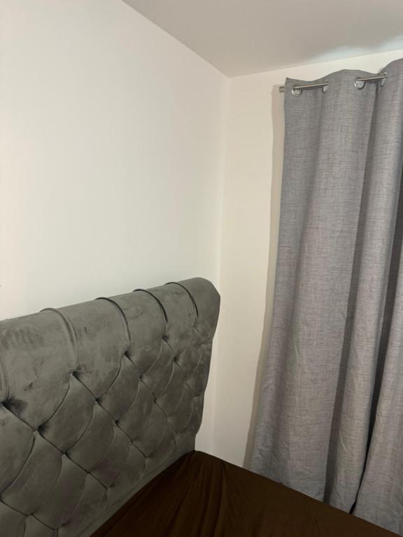 a couch sitting next to a window with a curtain at one bedroom-modern-luxury-private-free wifi-gravesend in Gravesend