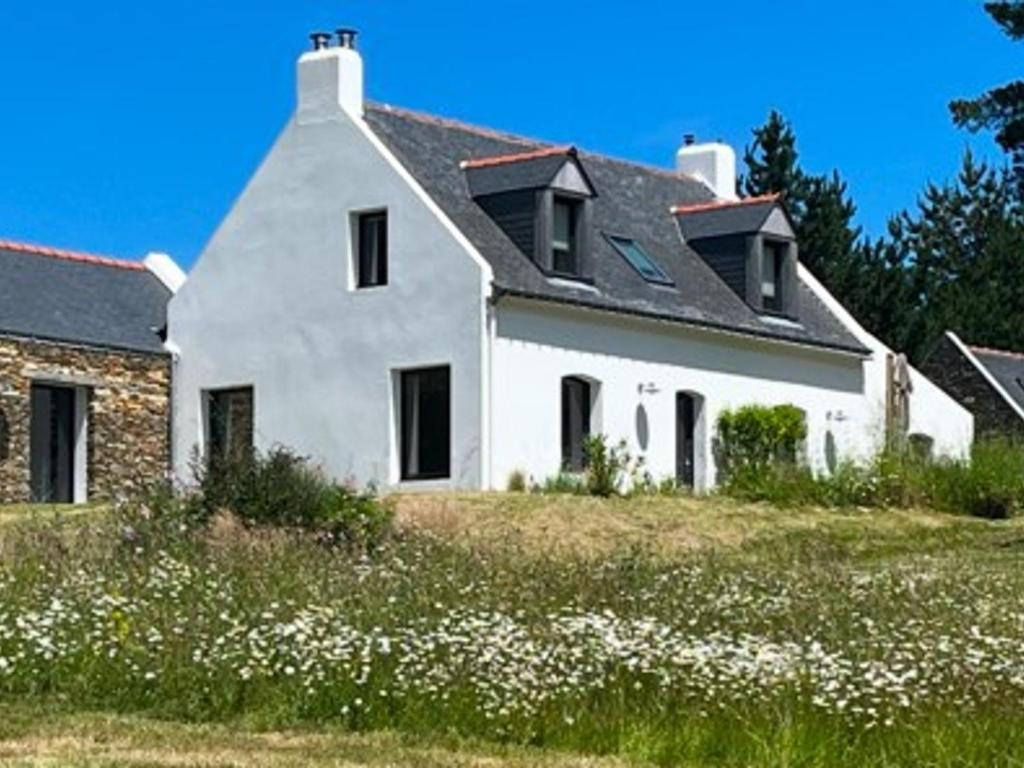 une maison blanche sur une colline avec un champ de fleurs dans l'établissement Maison lumineuse en pleine nature, 800 m de la mer, proche plage, jardin, WiFi, tout équipé. - FR-1-418-229, à Locmaria