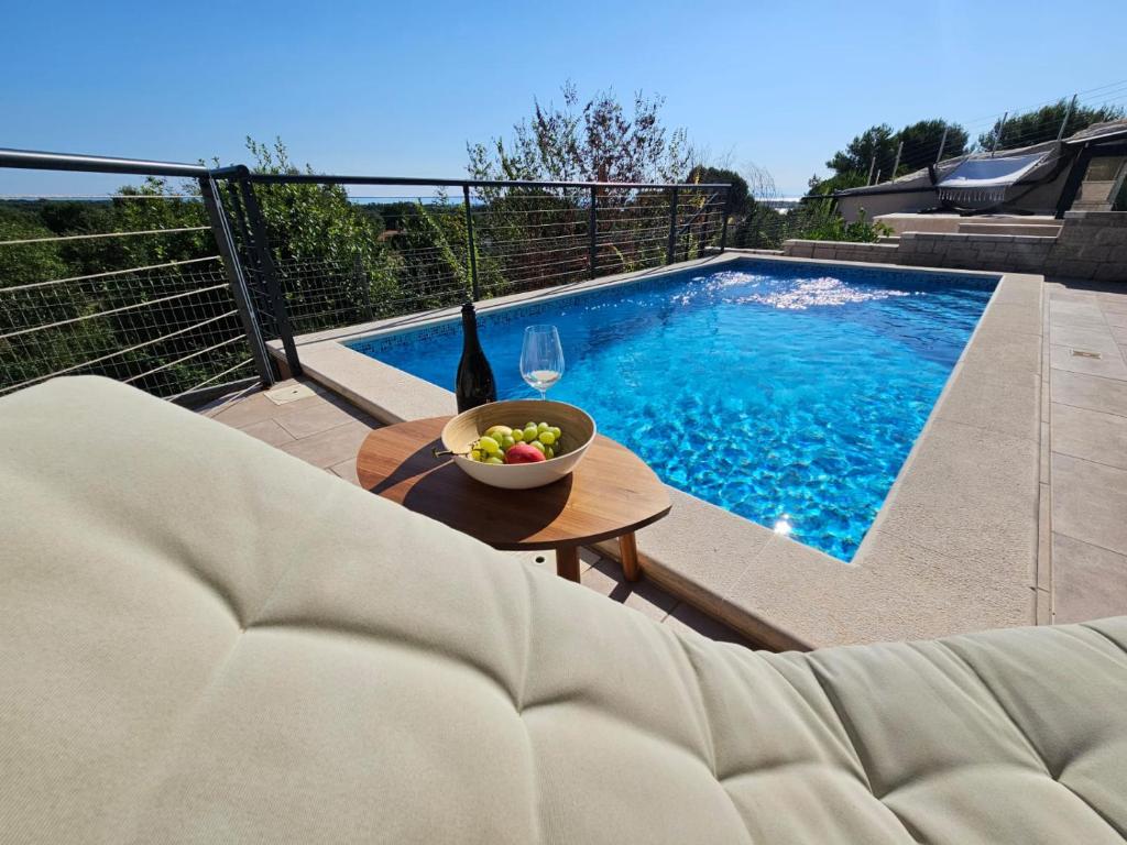 - un bol de fruits sur une table à côté de la piscine dans l'établissement Apartman Marlera s privatnim bazenom, à Ližnjan