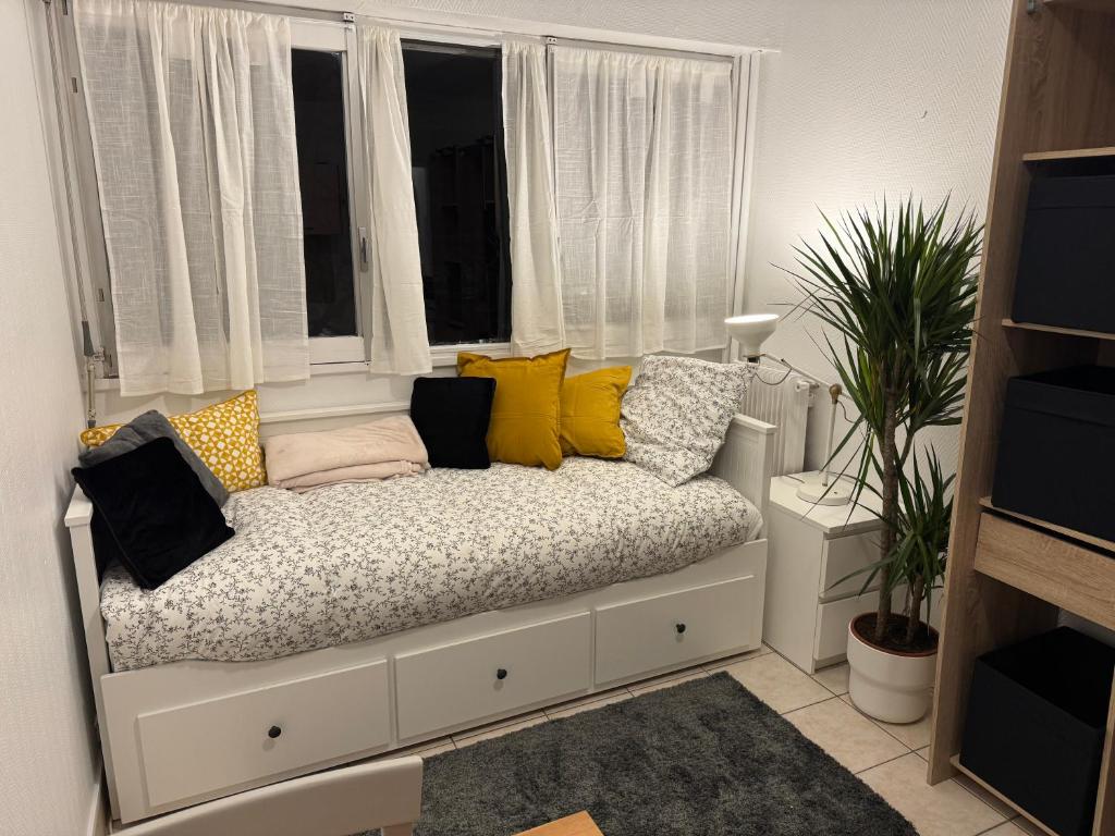 - un canapé avec des oreillers en face d'une fenêtre dans l'établissement Studio équipé Paris 20e, à Paris