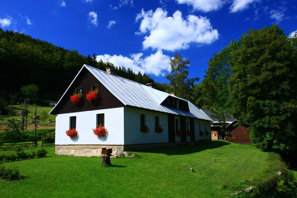 une maison blanche avec des fleurs rouges sur les fenêtres dans l'établissement Guest House U Lakomce, à Desná