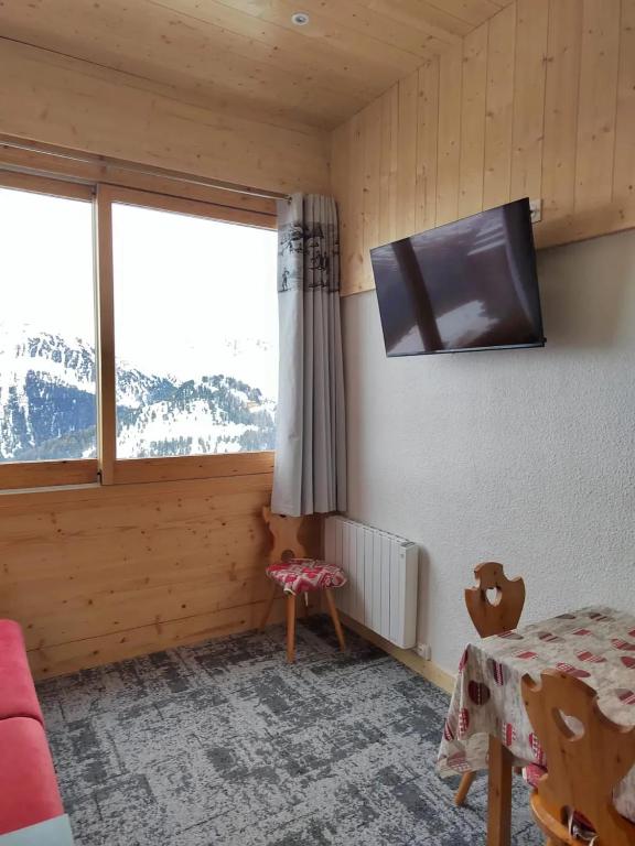 Cette chambre dispose d'une télévision, d'une table et d'une fenêtre. dans l'établissement Studio chaleureux à Aime la Plagne 25 m² en montagne, à Aime La Plagne