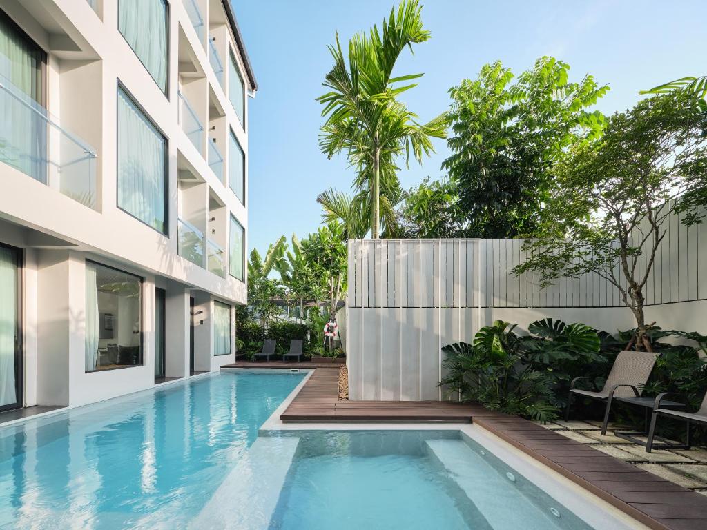 A narrow outdoor pool runs beside the hotel building, with a shallow square section and planted deck.