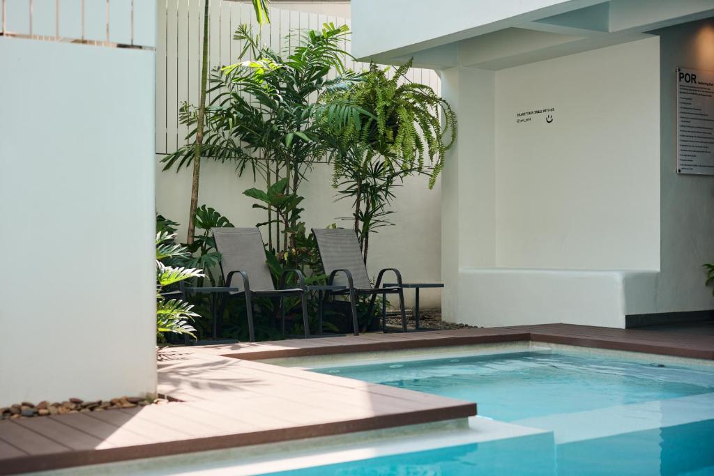 A compact courtyard pool surrounded by plants and reclining chairs.