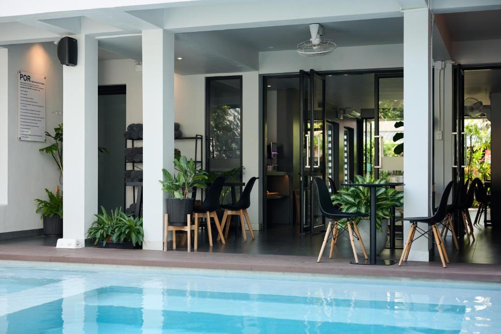 A turquoise pool beside a covered seating and dining area.