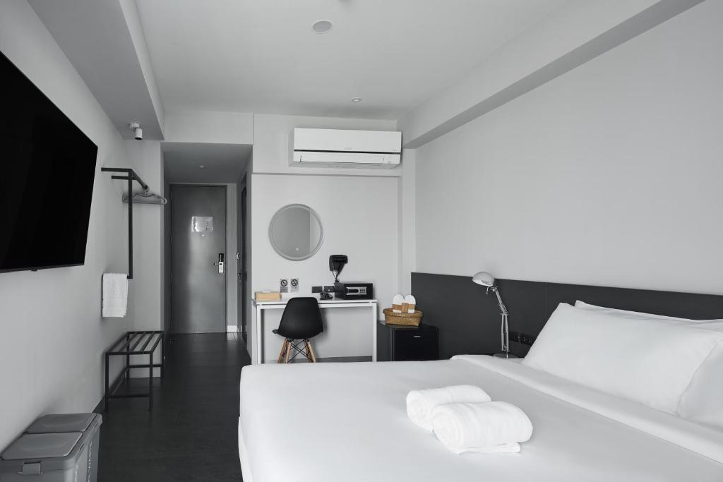 A modern bedroom with a white bed, compact desk and wall-mounted air conditioner.