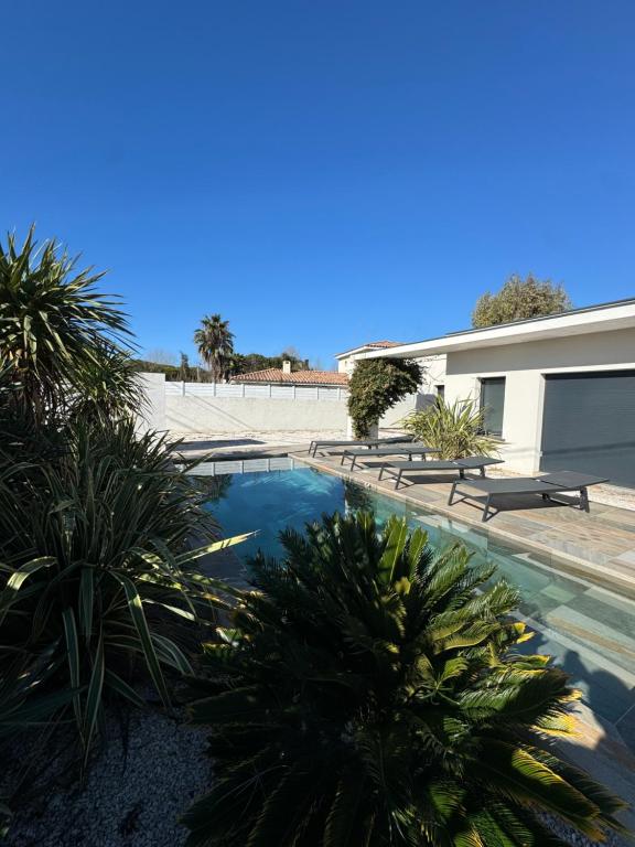 une piscine avec des palmiers à côté d'un immeuble dans l'établissement Villa spacieuse piscine 350 m de la plage, au Grau-dʼAgde