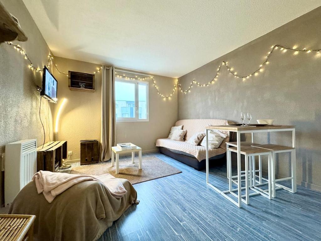 a living room with a bed and a table and a couch at Vacances à la mer - studio in Calais