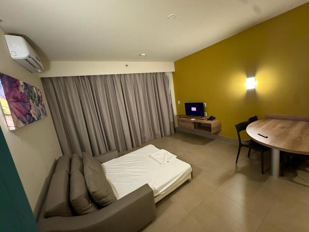 a hotel room with a bed and a table and a desk at Apto Solar das Águas Olimpia SP in Olímpia