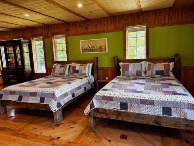 two beds in a room with green walls and wooden floors at le Studio in Tadoussac