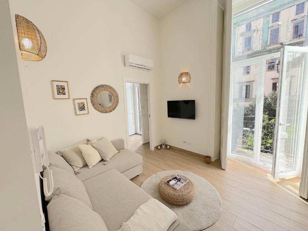een witte woonkamer met een bank en een tv bij UniHome Napoli in Napels