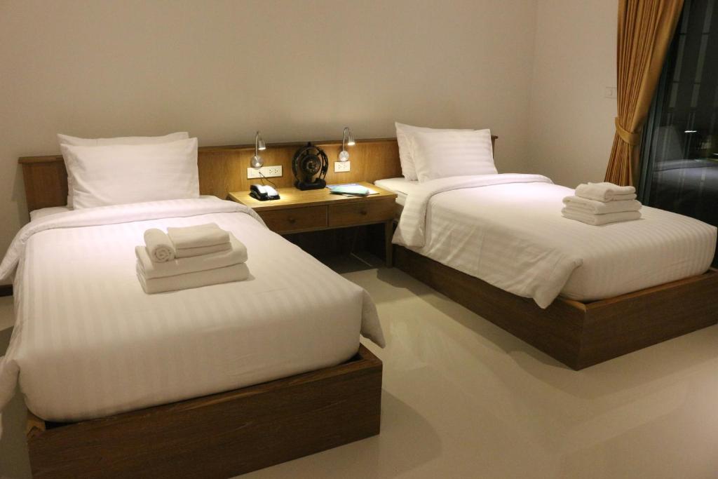 two beds in a hotel room with towels on them at Crystal Lamai Hotel in Lamai