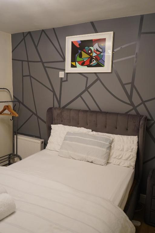 a bedroom with a bed with a painting on the wall at cozy lux apartments in Brimsdown Station