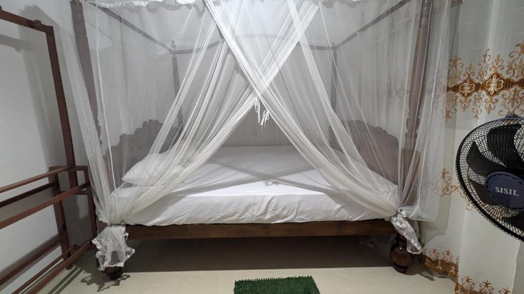 a canopy bed with white curtains in a room at Villa Dewdrops in Hikkaduwa