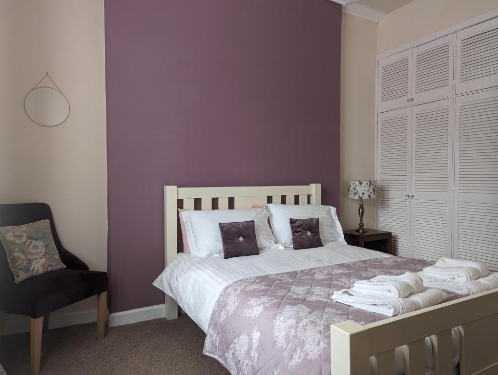 a bedroom with a bed with purple walls and a chair at Castle Brae Apartment in Stirling