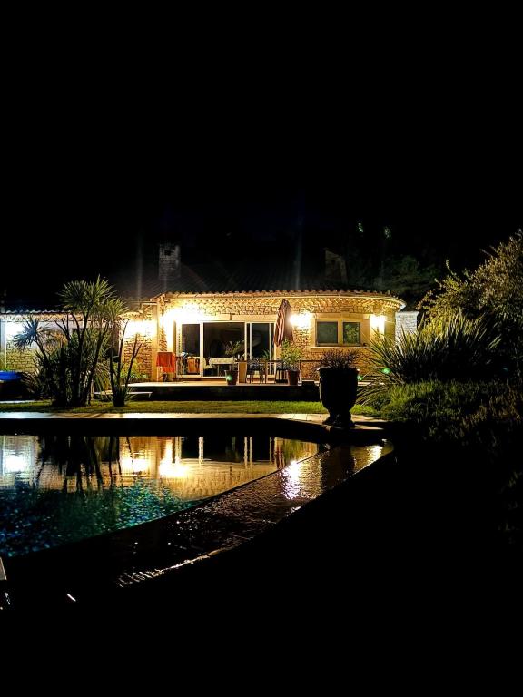 une maison la nuit avec un étang devant elle dans l'établissement Maison Entière, à Bagnols-sur-Cèze