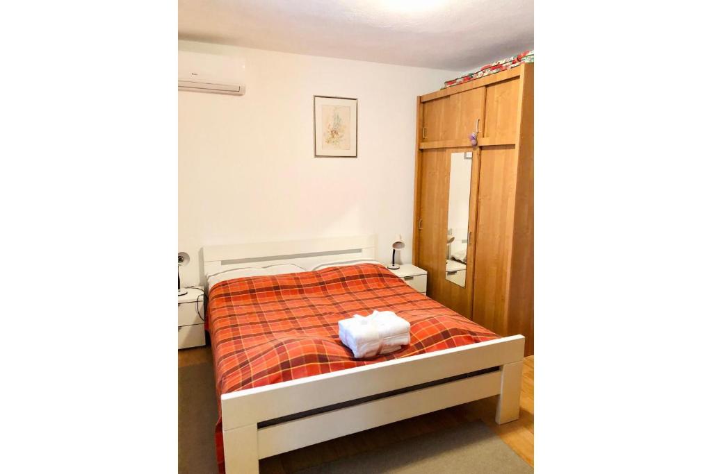 a bedroom with a bed with an orange blanket at Apartment Bonaca in Rogoznica