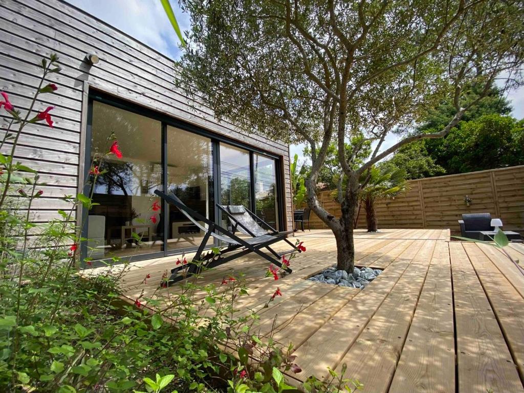 une maison avec un arbre sur une terrasse en bois dans l'établissement La Teste De Buch - Maison 2 Chambres -, à La Teste-de-Buch