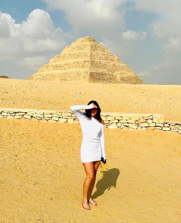 a woman standing in front of a pyramid at Horus pyramids view in Cairo