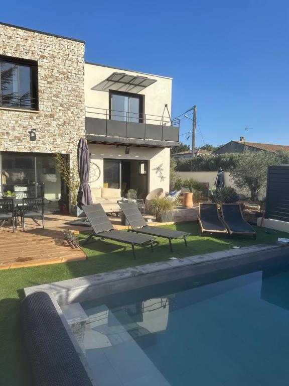 une piscine avec des chaises et une maison dans l'établissement Chambres d'hôte, à Châteauneuf-de-Gadagne
