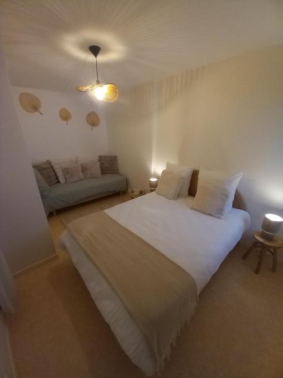 une chambre avec un grand lit blanc et un canapé dans l'établissement 2 Appartements au cœur de ville dans rue très calme, à Laruns