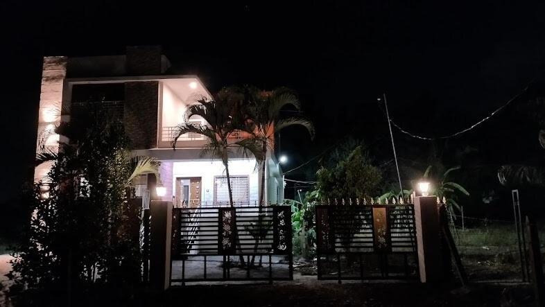 a house with a gate and a palm tree at night at Yogratna Classic in Pune